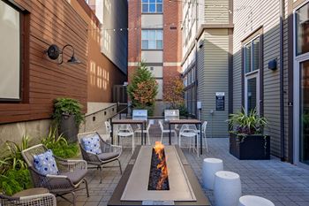 A patio with a fire pit and chairs.